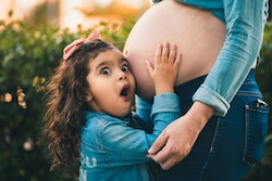 Girl touching the pregnant belly of her mother